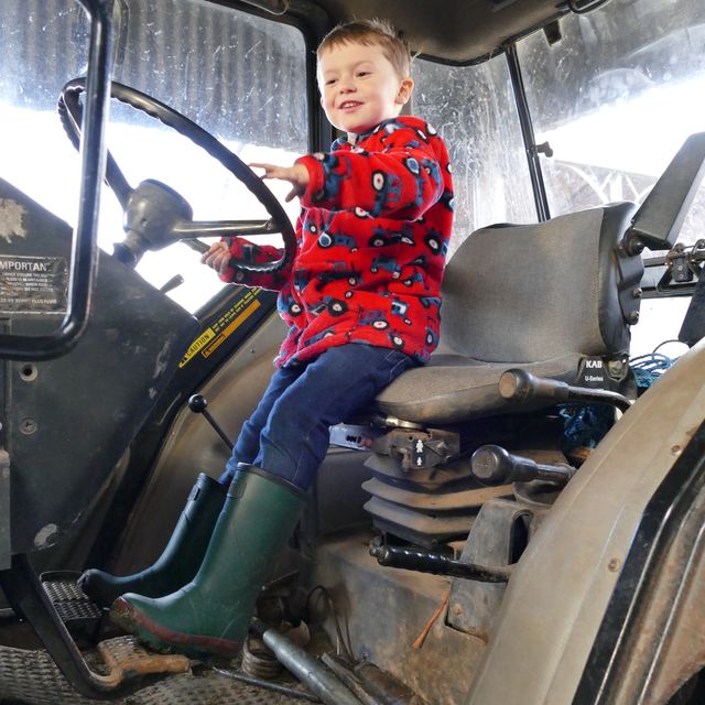 boy on tractor in green warm wellies